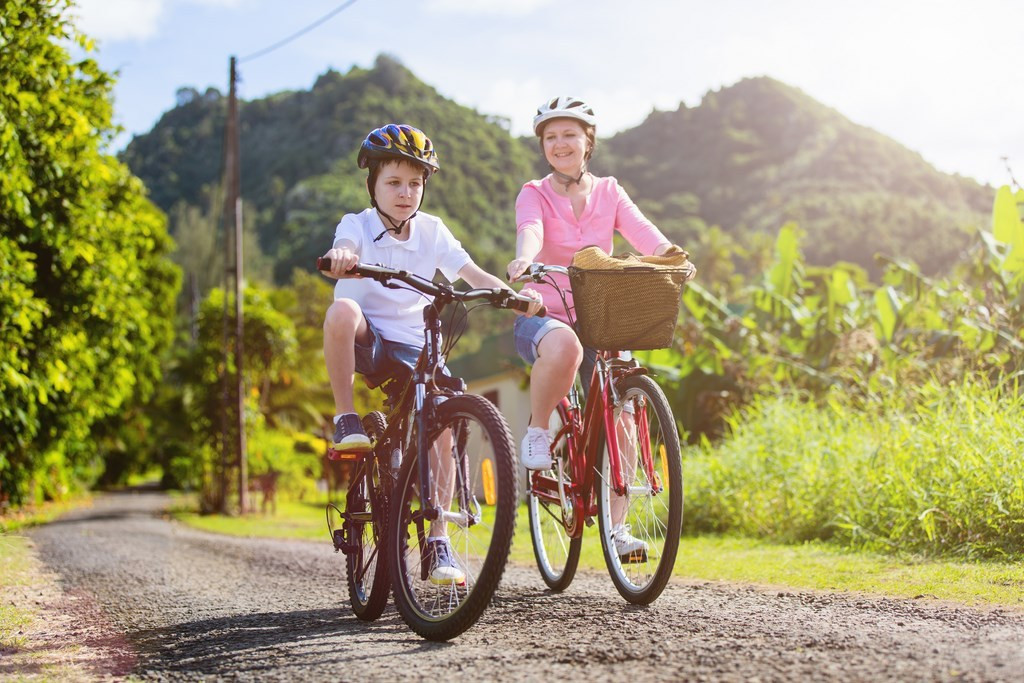 Family of mother and son biking at tropical settings having fun together